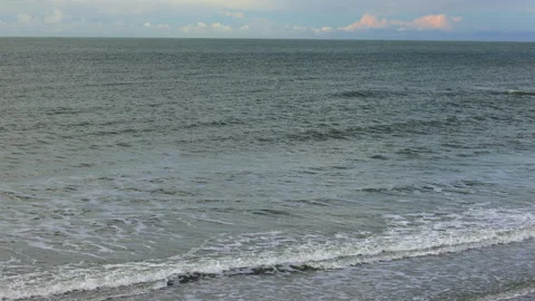 Sea Waves Gently Roll Onto a Secluded Shoreline Under a Cloudy Sky, Creating a Vidéo 340333275