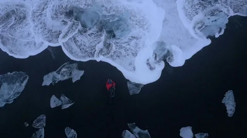 Sea waves gushing towards a man on the shore surrounded with iceberg lumps Stock Footage 74906211