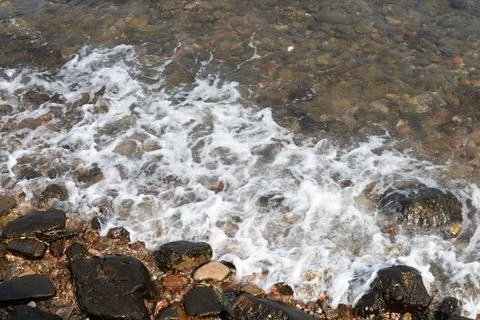 The sea waves hit the rocks, causing a splash of water. Stock Photos