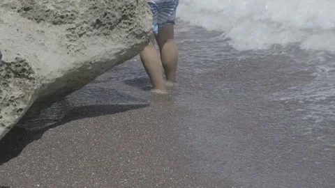 Sea waves hitting the legs of a young tourist in a swimsuit Stock Footage