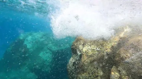 Sea ​​waves hitting the rock and creating bubbles, underwater shot Video stock 289577304