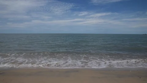 Sea waves lapping and make white foam on the beach with cloudy blue sky. Stock Footage 132891966