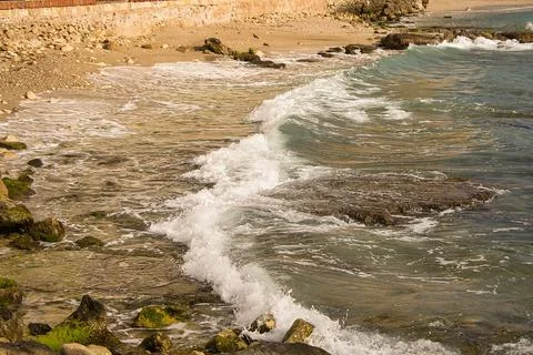 Sea waves lash line impact rock on the beach, located in Alicante 스톡 사진
