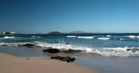 Sea waves over sand and stone beach Parque Natural de Corralejo on Fuerteventura Stockbeeldmateriaal 103535538
