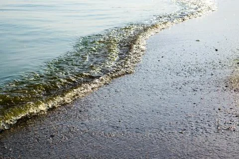 Sea waves with rays of light and sandy beach Stock Photos