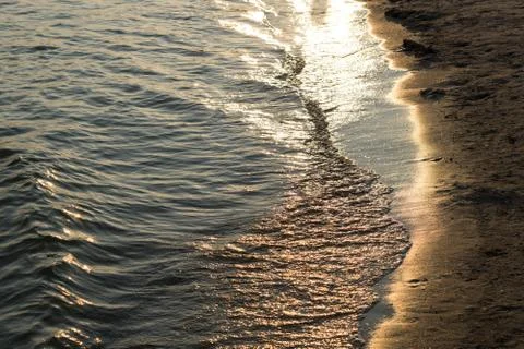 Sea waves with rays of light and sandy beach Stock Photos