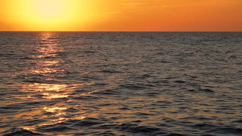 Sea waves with reflection of gold sunlight on the orange background. Stock Footage 243645741