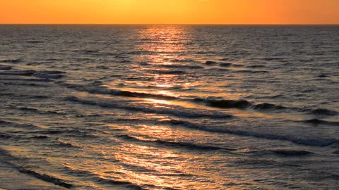 Sea waves with reflection of gold sunlight on the orange background. 库存影片 243846221