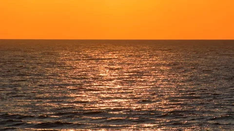 Sea waves with reflection of gold sunlight on the orange background. 库存影片 243892661