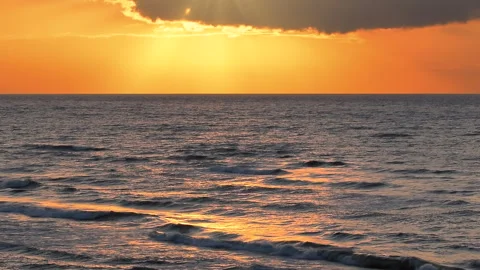 Sea waves with reflection of gold sunlight on the orange background. 库存影片 243904127