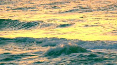 Sea waves with reflection of gold sunset light, by the beach. Stock Footage 238733147