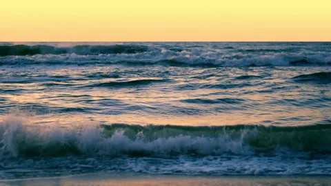 Sea waves with reflection of gold sunset light, by the beach. Stock Footage 238733919