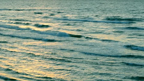 Sea waves with reflection of gold sunset light, by the beach. Stock Footage 239604261