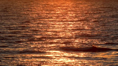 Sea waves with reflection of gold sunset light, by the beach, slow motion. Stock Footage 243893123