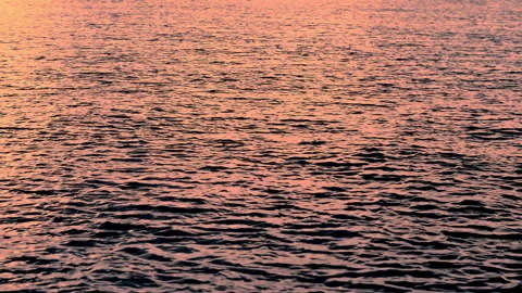 Sea waves with reflection of orange sunset light, by the beach, slow motion. Stock Footage 240985717