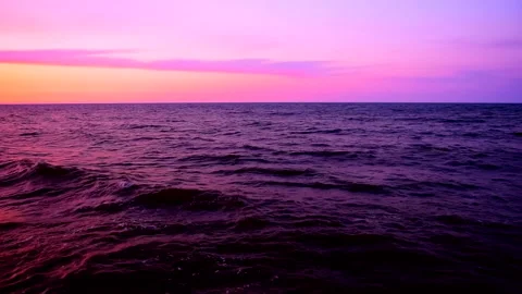 Sea waves with reflection of pink sunset light on the purple background. Stock Footage 239426115