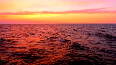 Sea waves with reflection of red sunset light on the sunset background. 库存影片 239050822