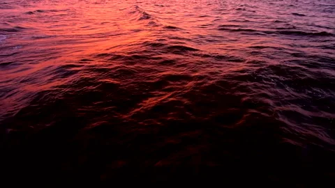 Sea waves with reflection of red sunset light, by the beach, slow motion. Stock Footage 244213800