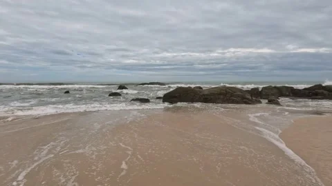 Sea waves rocky sandy empty beach cloudy day Video stock 243238139