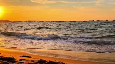 Sea waves roll along sandy beach shore at bright golden sunset hour. Stock Footage 344925472