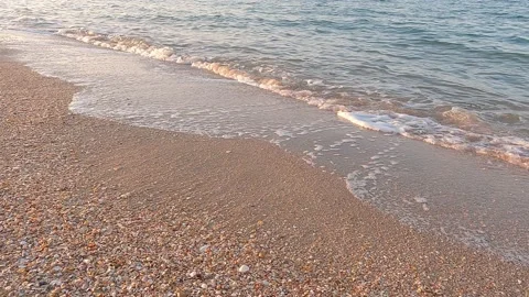 Sea waves roll onto beach in light of setting sun Stock Footage 165199959