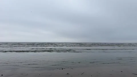Sea waves roll onto a sandy beach on a cloudy day Stock Footage 294586653