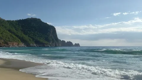 Sea waves roll on the sandy shore at the foot of the mountain Stock Footage 221858695