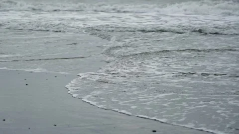 Sea waves roll onto the sandy shore in cloudy weather. Stock Footage 262968216