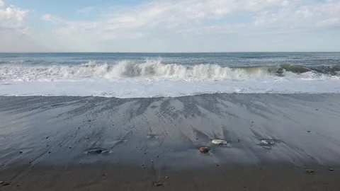 Sea waves roll onto the sandy shore. The girl runs towards the waves Stock Footage 265021505