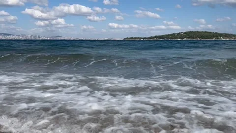 Sea Waves Rolling onto a Pebbled Shore with Island View Stock Footage 342355155