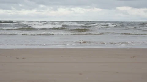Sea waves rolling on sand beach under overcast cloudy sky in Latvia coast Stock Footage 325974478