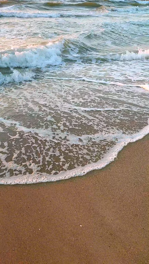 Sea waves rolling onto sandy beach of seashore on sunny morning at dawn Vertical Stock Footage 268035612
