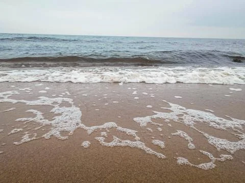 Sea waves rolling on sandy beach shore Stock Photos