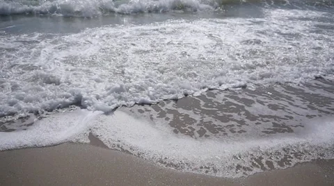 Sea waves running on the sandy shore producing a foam in slow motion Stock Footage 62099530