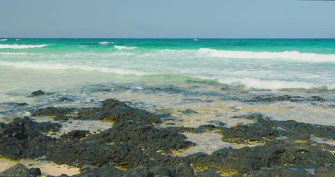 Sea waves rushing over black volcanic stones and white sand foaming. Nature Stock Footage 201719098