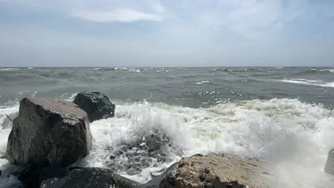 Sea waves with splashes and foam crash against the rocky shore Video stock 159187267