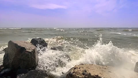 Sea waves with splashes and foam crash against the rocky shore Video stock 159187387