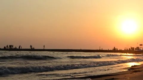 Sea waves with splashes crash on seashore. Black silhouette of pier Stock Footage 168826432