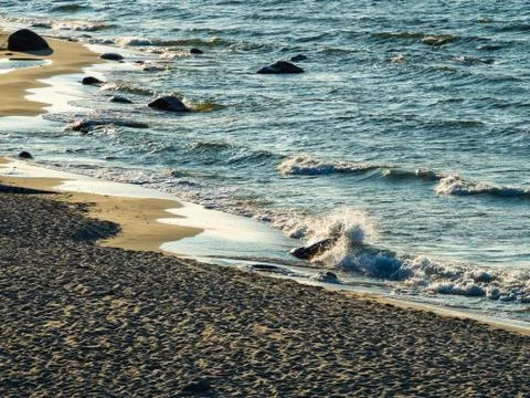 Sea waves with splashes at sunset or sunrise. Ocean waves washing coast sand  Stock Photos