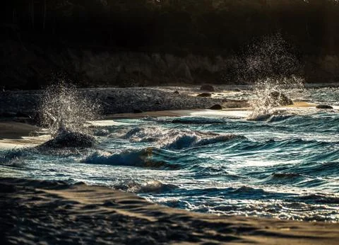 Sea waves with splashes at sunset or sunrise. Ocean waves washing coast sand  Stock Photos