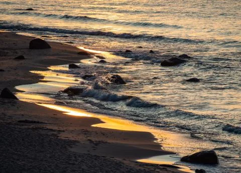 Sea waves with splashes at sunset or sunrise. Ocean waves washing coast sand  Stock Photos