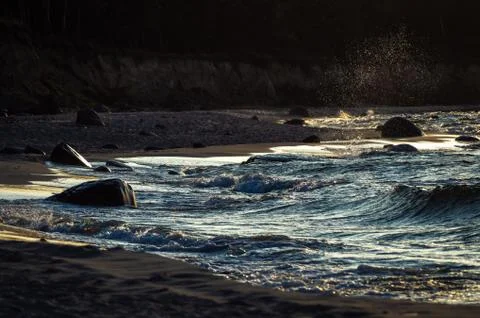 Sea waves with splashes at sunset or sunrise. Ocean waves washing coast sand  Stock Photos