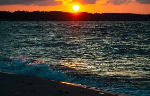 Sea waves with splashes at sunset or sunrise. Ocean waves washing coast sand  Stock Photos
