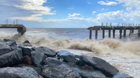 Sea waves striking damaged pier wide shot beside rocky shore Stock Footage 345361668