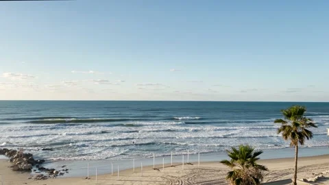 Sea waves in a sunny sunset, empty beach, lonely surfer coming out Stock Footage 147012557