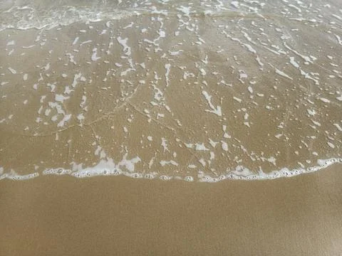 Sea waves on the surface of the sandy beach.Soft waves of blue sea and sand  Stock Photos