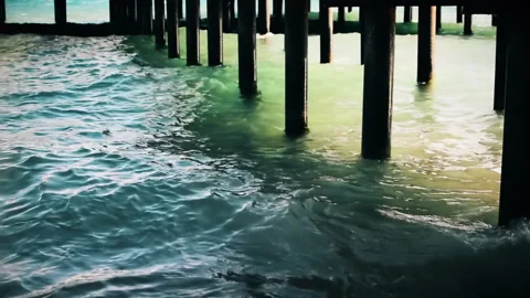 Sea waves under pillars of pier located on beach. Video stock 152957036