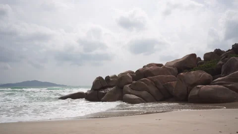 Sea waves wash over sandy beach and big rocks slowly Stock Footage 163517852