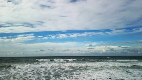 Sea waves wash the sandy beach. There is a blue sky with fluffy white clouds on Stock Footage 239227765