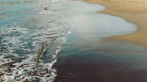 Sea waves wash the sandy smooth beach on a sunny day during sunset. Stock Footage 107902923
